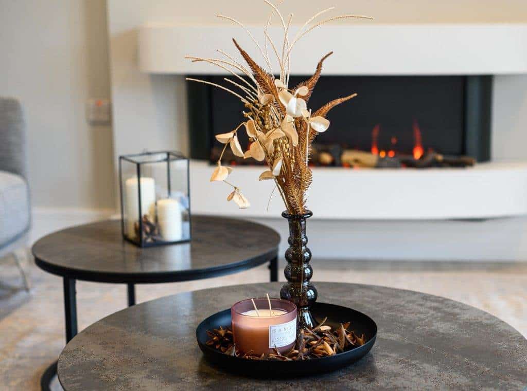 Modern decorative dried flower arrangement with candle in a black bowl in living room.