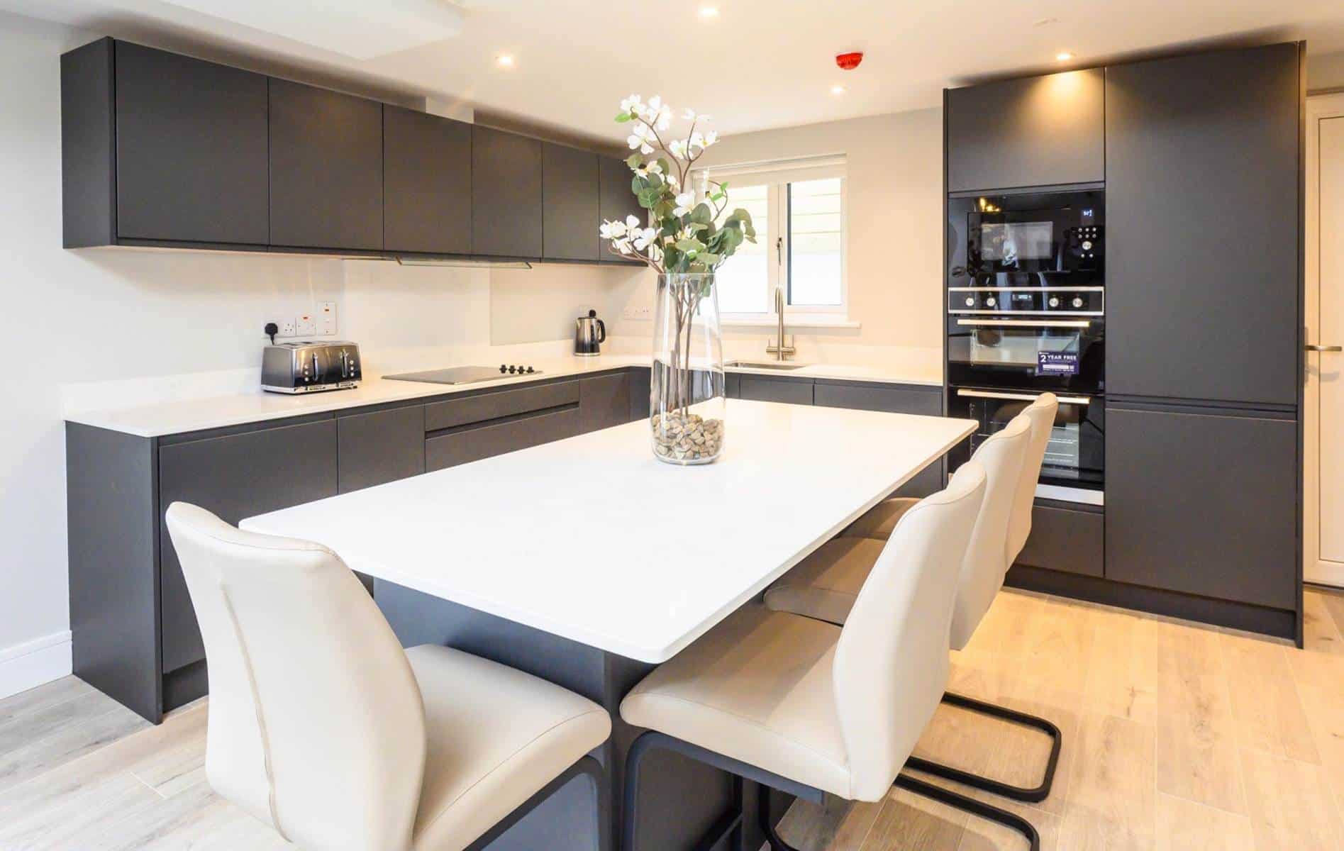Modern kitchen with black cabinets and white island, bright and spacious design.